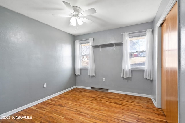 unfurnished room with visible vents, a healthy amount of sunlight, wood finished floors, and a ceiling fan