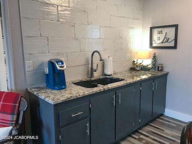 kitchen featuring light stone countertops, dark hardwood / wood-style flooring, blue cabinets, and sink