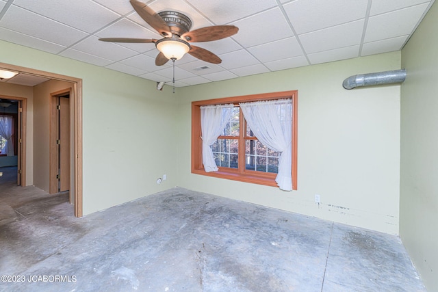 spare room featuring a paneled ceiling, ceiling fan, and concrete flooring