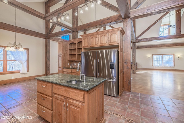 kitchen with plenty of natural light, stainless steel fridge, sink, and a center island with sink