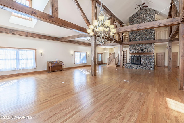 unfurnished living room featuring ceiling fan with notable chandelier, wood-type flooring, a fireplace, and high vaulted ceiling