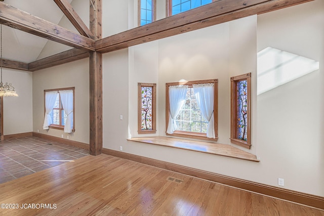 unfurnished living room featuring high vaulted ceiling, wood-type flooring, and a notable chandelier