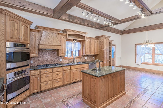 kitchen featuring an inviting chandelier, sink, decorative backsplash, an island with sink, and appliances with stainless steel finishes