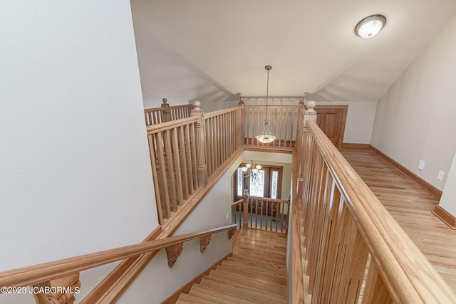 staircase with a chandelier and hardwood / wood-style flooring