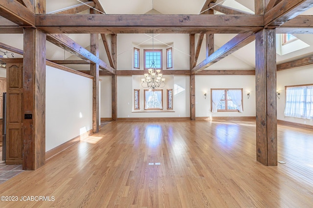 interior space with plenty of natural light, high vaulted ceiling, light wood-type flooring, and an inviting chandelier