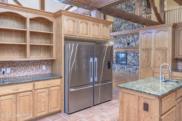 kitchen featuring stainless steel refrigerator, sink, dark stone countertops, and light tile patterned flooring