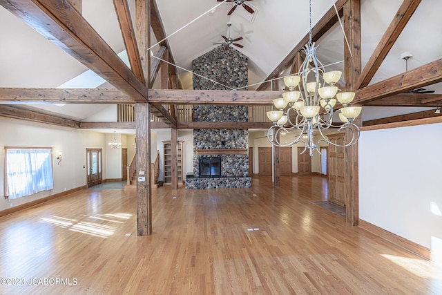 unfurnished living room featuring ceiling fan with notable chandelier, wood-type flooring, a fireplace, and high vaulted ceiling