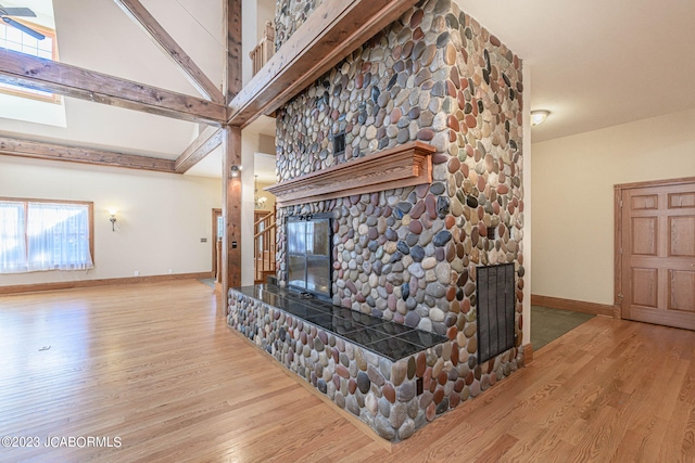 living room with a tile fireplace, beamed ceiling, and wood-type flooring