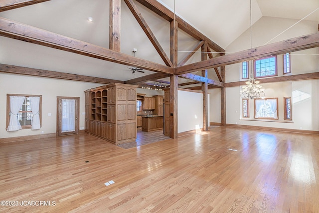 unfurnished living room with light wood-type flooring, ceiling fan with notable chandelier, high vaulted ceiling, and beamed ceiling