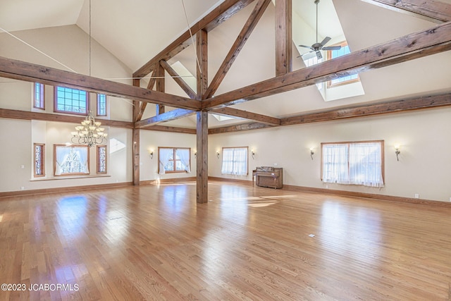 interior space with plenty of natural light, light hardwood / wood-style floors, ceiling fan with notable chandelier, and high vaulted ceiling