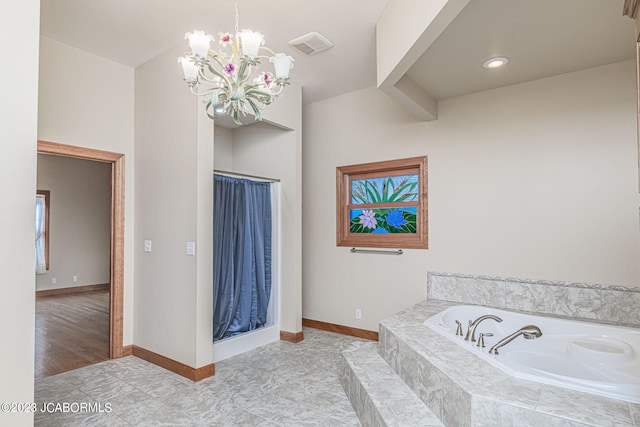 bathroom with a relaxing tiled tub and a chandelier