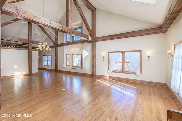 unfurnished living room with light hardwood / wood-style flooring, high vaulted ceiling, and an inviting chandelier