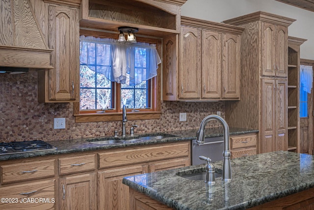 kitchen featuring stainless steel gas stovetop, dark stone countertops, and sink