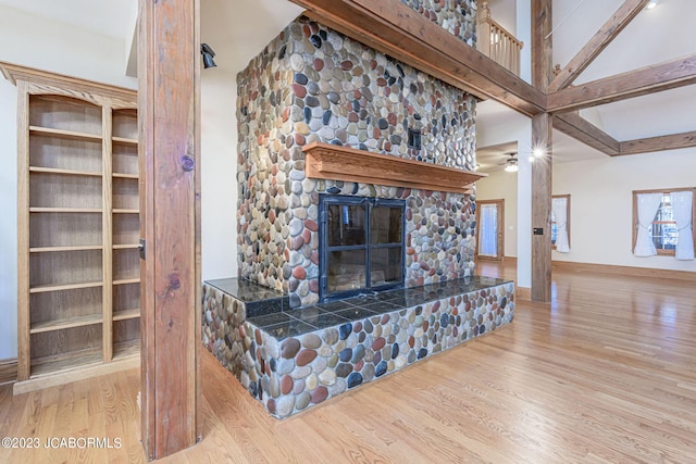 living room featuring a stone fireplace, ceiling fan, and light hardwood / wood-style flooring