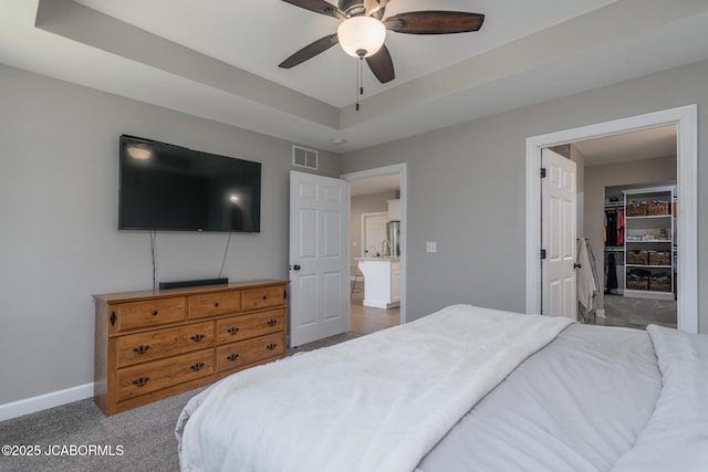 bedroom featuring ceiling fan, carpet flooring, visible vents, baseboards, and a raised ceiling