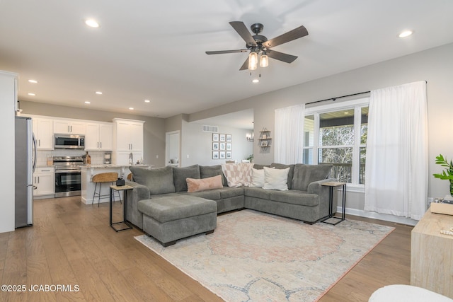 living area featuring a ceiling fan, recessed lighting, visible vents, and wood finished floors