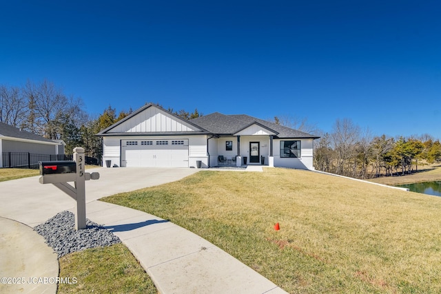 view of front of property featuring a garage, concrete driveway, fence, board and batten siding, and a front yard