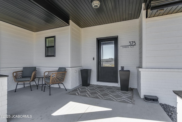 doorway to property with covered porch and brick siding