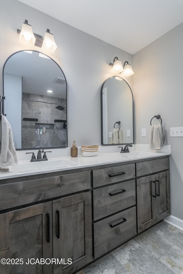 full bath with a tile shower, double vanity, a sink, and visible vents