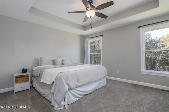 bedroom featuring visible vents, baseboards, a raised ceiling, ceiling fan, and carpet floors