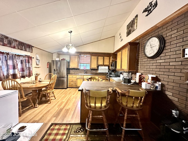 kitchen featuring kitchen peninsula, appliances with stainless steel finishes, a paneled ceiling, decorative backsplash, and a chandelier