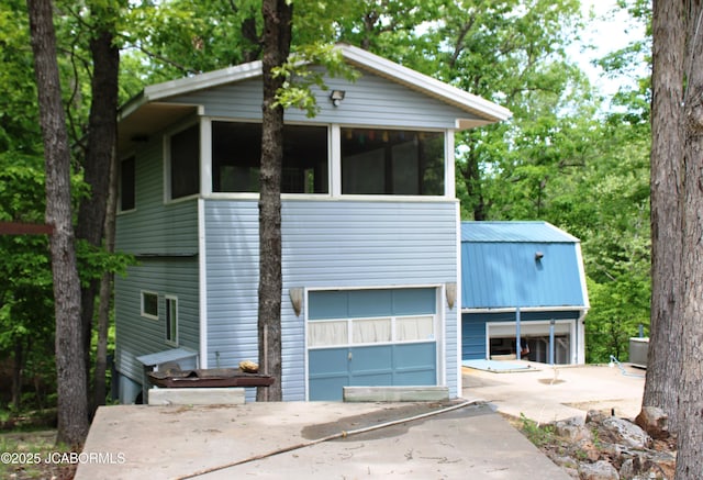 6640 Doe Vw, Steedman, MO 65077 - view of front facade with concrete driveway, an attached garage, metal roof, and a sunroom