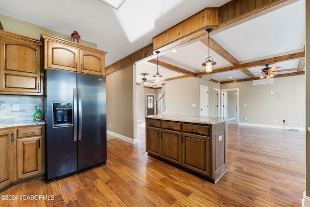 kitchen with backsplash, ceiling fan, stainless steel fridge, beamed ceiling, and a kitchen island