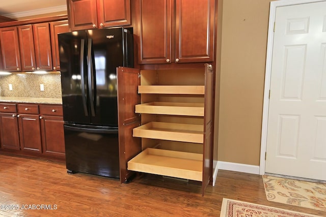 kitchen featuring baseboards, dark wood-style flooring, freestanding refrigerator, dark brown cabinets, and decorative backsplash