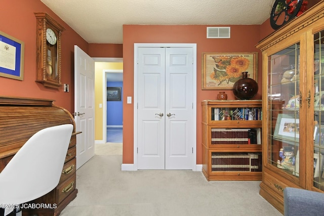 carpeted home office featuring visible vents and a textured ceiling