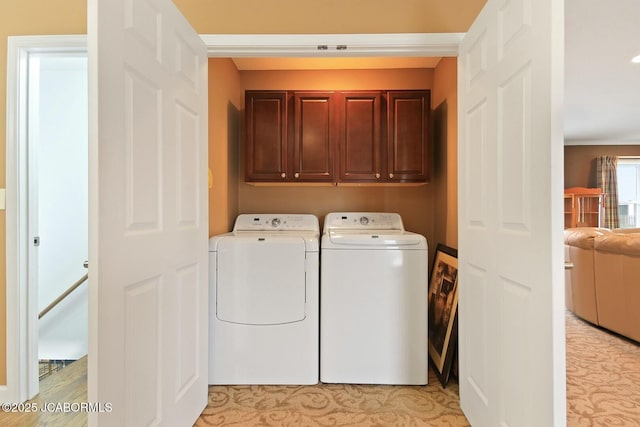 clothes washing area with washer and dryer and cabinet space