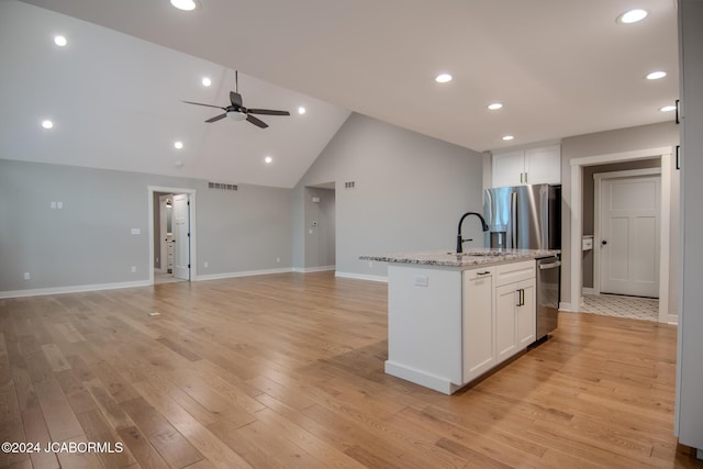 kitchen with a center island with sink, stainless steel appliances, open floor plan, and white cabinetry