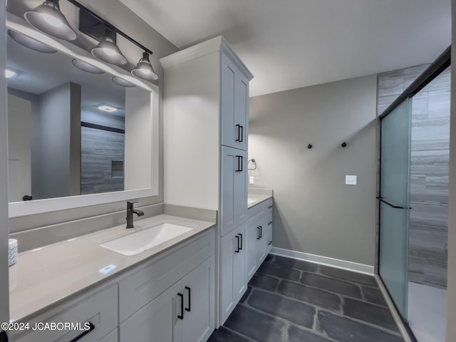 full bathroom with vanity, a shower stall, and baseboards