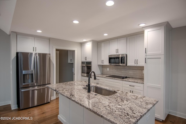 kitchen with decorative backsplash, wood finished floors, appliances with stainless steel finishes, and a sink