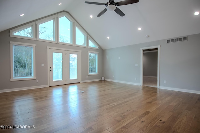 unfurnished living room with visible vents, baseboards, high vaulted ceiling, and wood finished floors