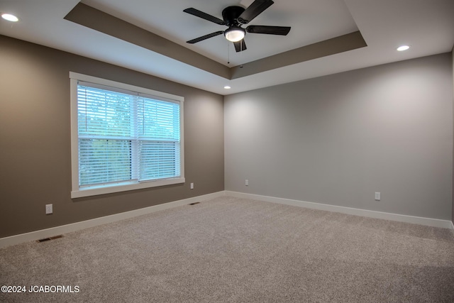 unfurnished room with a raised ceiling, carpet flooring, baseboards, and visible vents