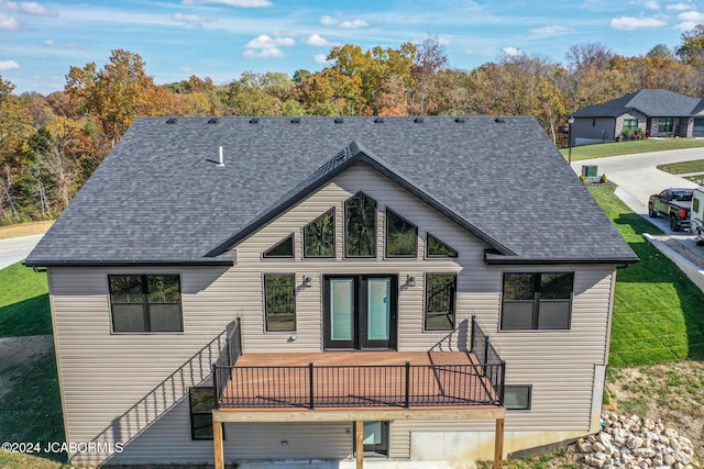 rear view of property featuring a wooden deck, a lawn, and a shingled roof