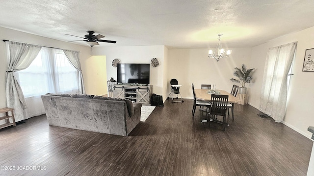 living room featuring dark hardwood / wood-style floors, ceiling fan with notable chandelier, and a textured ceiling