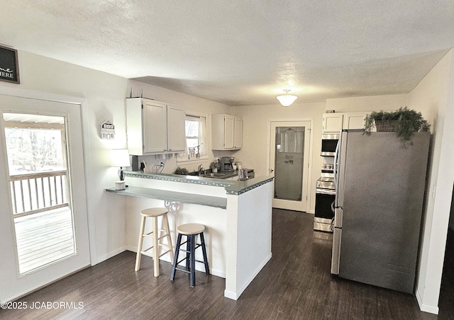 kitchen with white cabinetry, appliances with stainless steel finishes, kitchen peninsula, and a breakfast bar area