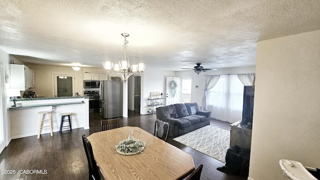 dining room with dark wood-type flooring, ceiling fan with notable chandelier, and a textured ceiling