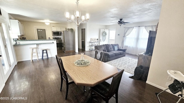 dining area with ceiling fan with notable chandelier, dark wood-type flooring, and a textured ceiling