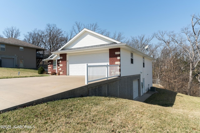 view of home's exterior featuring brick siding, a lawn, driveway, and cooling unit