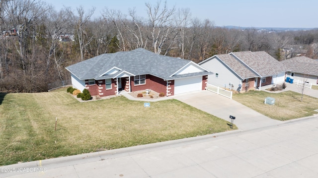 view of front of property featuring brick siding, concrete driveway, a front yard, a view of trees, and an attached garage