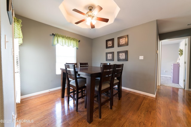 dining space with a ceiling fan, wood finished floors, and baseboards