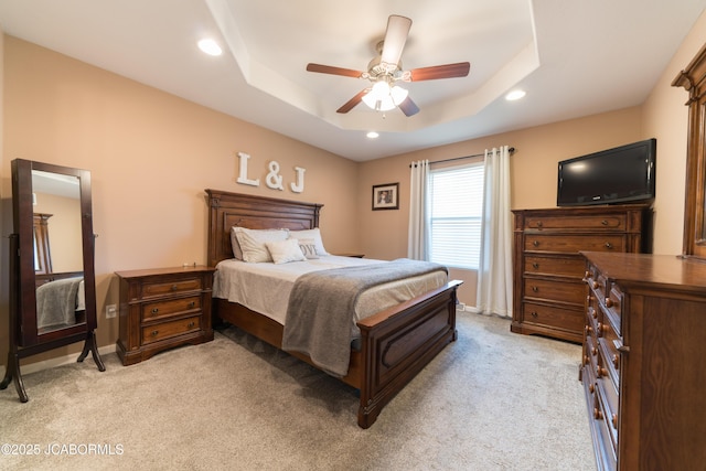 bedroom with light carpet, a tray ceiling, recessed lighting, baseboards, and ceiling fan