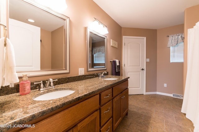 full bathroom with double vanity, visible vents, baseboards, and a sink