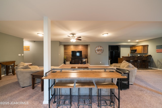 dining area featuring light colored carpet, baseboards, bar area, and a ceiling fan