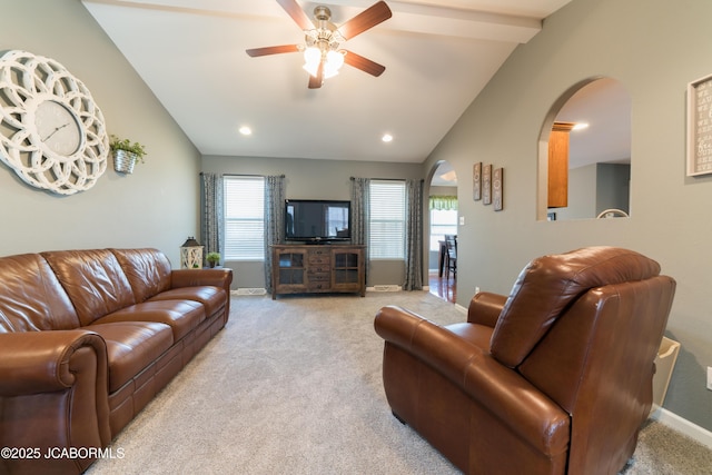 living room featuring a ceiling fan, arched walkways, carpet floors, baseboards, and vaulted ceiling with beams