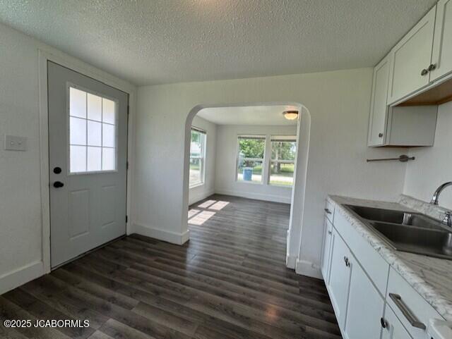210 Academy St, Clarksburg, MO 65025 - kitchen featuring arched walkways, a textured ceiling, dark wood-style floors, white cabinets, and light stone counters
