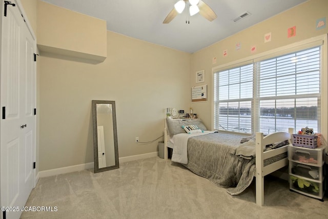 bedroom with a water view, light carpet, and ceiling fan