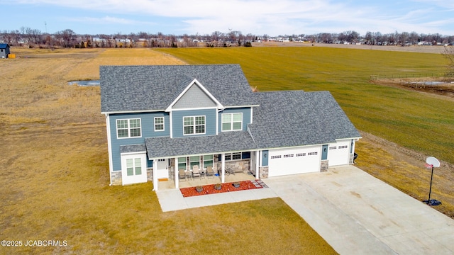 view of front of home featuring a rural view, a garage, a front yard, and covered porch